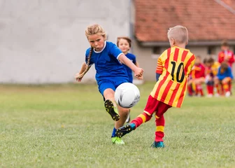 Foto op Plexiglas Voetbal Kindervoetbalvoetbal - klein meisje schiet bal op voetbalveld