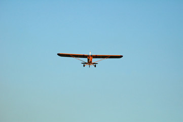 yellow single engine monoplane approaching for landing