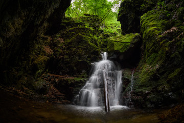 Fototapeta na wymiar Waterfall and rocks covered with moss in the forest