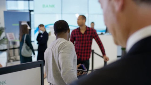 Worker at customer service desk assisting queue of customers in modern bank