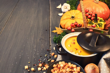 Pumpkin creme soup in ceramic pan on dark wood, space