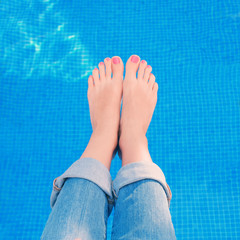 Woman wearing blue jeans while relaxing by the swimming pool.