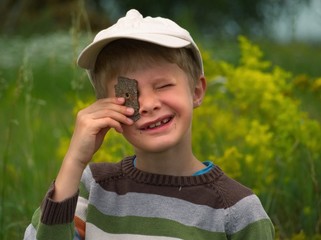 Little boy in a baseball cap looks through a hole in the bark of a tree