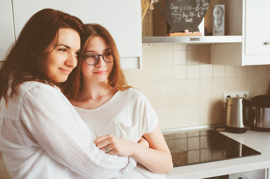 Mother Having Breakfast With Teen Daughter At Home In Modern White Kitchen. Casual Lifestyle In Real Life Interior