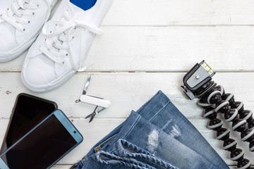 Travel accessories such as sneaker , jean , mobile phone on old white wooden  background