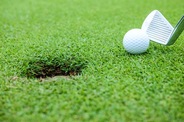 White color golf ball on green near hole at the morning time
