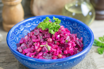 Vinaigrette vegan nutritional vegetarian salad with boiled vegetables in blue ceramic bowl on wooden rustic table. Traditional russian cuisine
