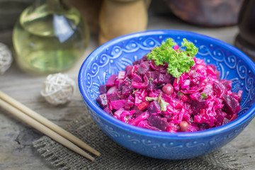 Vinaigrette vegan nutritional vegetarian salad with boiled vegetables in blue ceramic bowl on wooden rustic table. Traditional russian cuisine