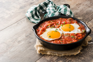 Mexican breakfast: Huevos rancheros in iron frying pan on wooden table