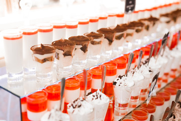 Delicious and tasty dessert table with cupcakes shots at reception closeup