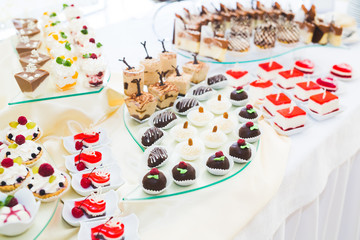 Delicious sweets on wedding candy buffet with desserts, cupcakes