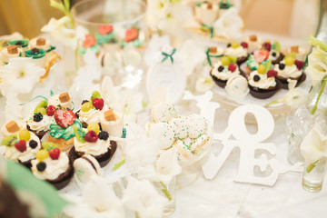 Delicious and tasty dessert table with cupcakes shots at reception closeup