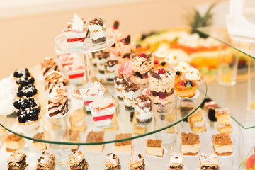 Delicious and tasty dessert table with cupcakes shots at reception closeup