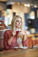 Young fashion woman drinks tea a cafe. caucasian woman sitting in act to drink a cup of tea