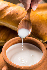 Clay pot with milk and baguette on wooden table