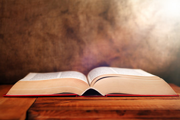 Old Book with light on old vintage table. Selective focus