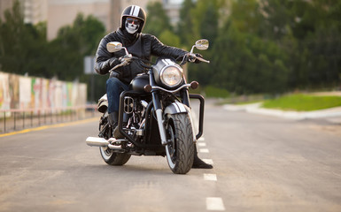 Obraz na płótnie Canvas biker in mask sitting unknown on big chopper bike on road