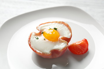 Plate with tasty egg in ham on table