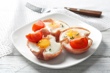 Plate with tasty eggs in ham on table