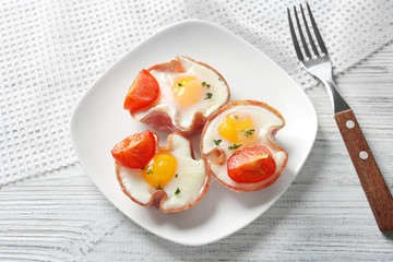 Plate with tasty eggs in ham on table