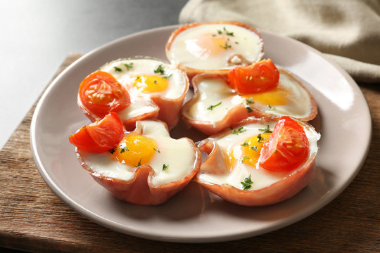 Tasty eggs with tomatoes in ham on plate, closeup