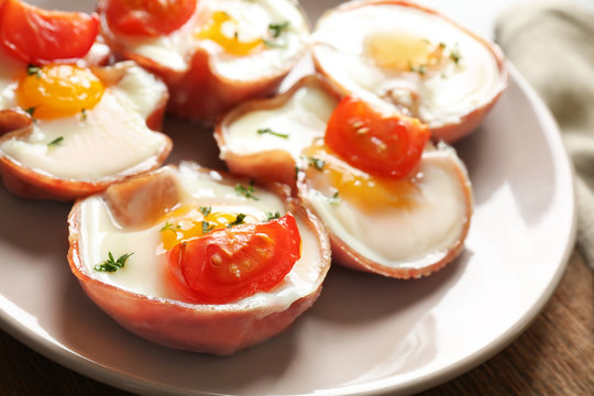 Tasty eggs with tomatoes in ham on plate, closeup