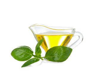 Gravy boat with oil and green basil leaves on white background