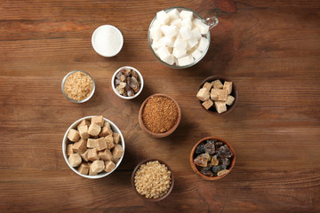 Various kinds of sugar in bowls on wooden table