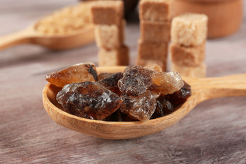 Brown candy sugar in spoon on wooden table