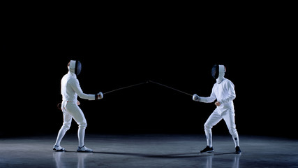 Two Young Professional Fencers Greet Audience, Put on Masks and Start Sword Fighting Match. Shot...