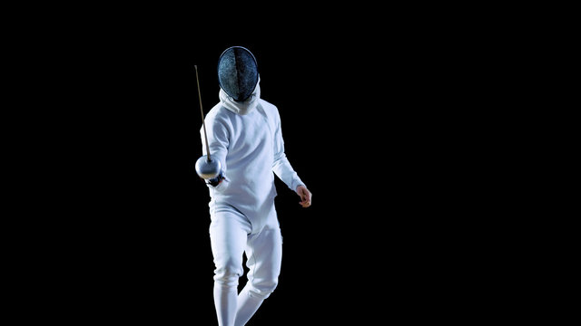 Portrait Shot of a Fully Equipped Skilled Fencer Training with a Foil. He Practices Attack, defense,  Leap, Thrust and Lunge. Shot Isolated on Black Background.
