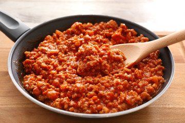 Meat sauce in frying pan on wooden background