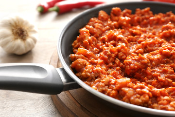 Meat sauce in frying pan on wooden background