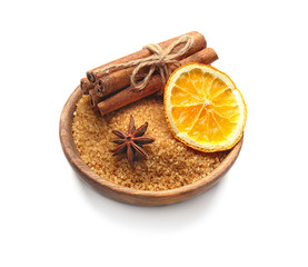 Wooden plate with cinnamon sugar and sticks on white background