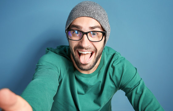 Young Man Taking Selfie Against Color Wall Background