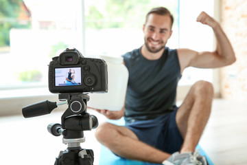 Young sports blogger recording video on camera at home