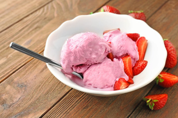 Bowl with delicious strawberry ice-cream on wooden background