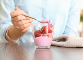 Woman eating delicious strawberry ice-cream in cafe
