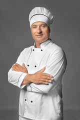 Male chef in uniform on grey background