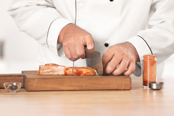 Male chef cutting meat in kitchen, closeup