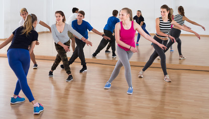 Fototapeta na wymiar Group of positive smiling teenagers dancing in classroom