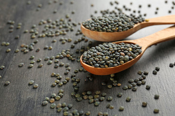 Spoons with healthy lentils on grey background
