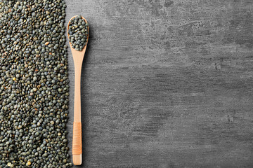 Composition with spoon and healthy lentils on grey background