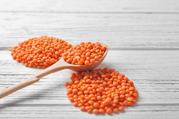 Spoon with healthy lentils on wooden background
