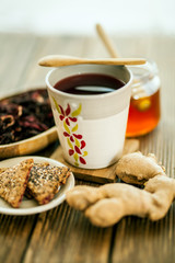 Tea from hibiscus with honey, ginger root and biscuits on a wooden base