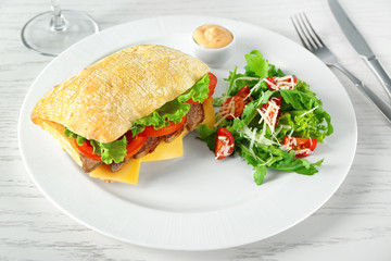 Plate with steak sandwich and vegetable salad on table