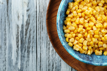 Corn kernels in bowl on wooden background