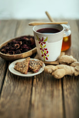 Tea from hibiscus with honey, ginger root and biscuits on a wooden base