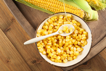 Corn kernels in bowl on wooden background