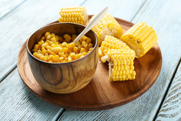 Corn kernels and cut cob on tray against wooden background